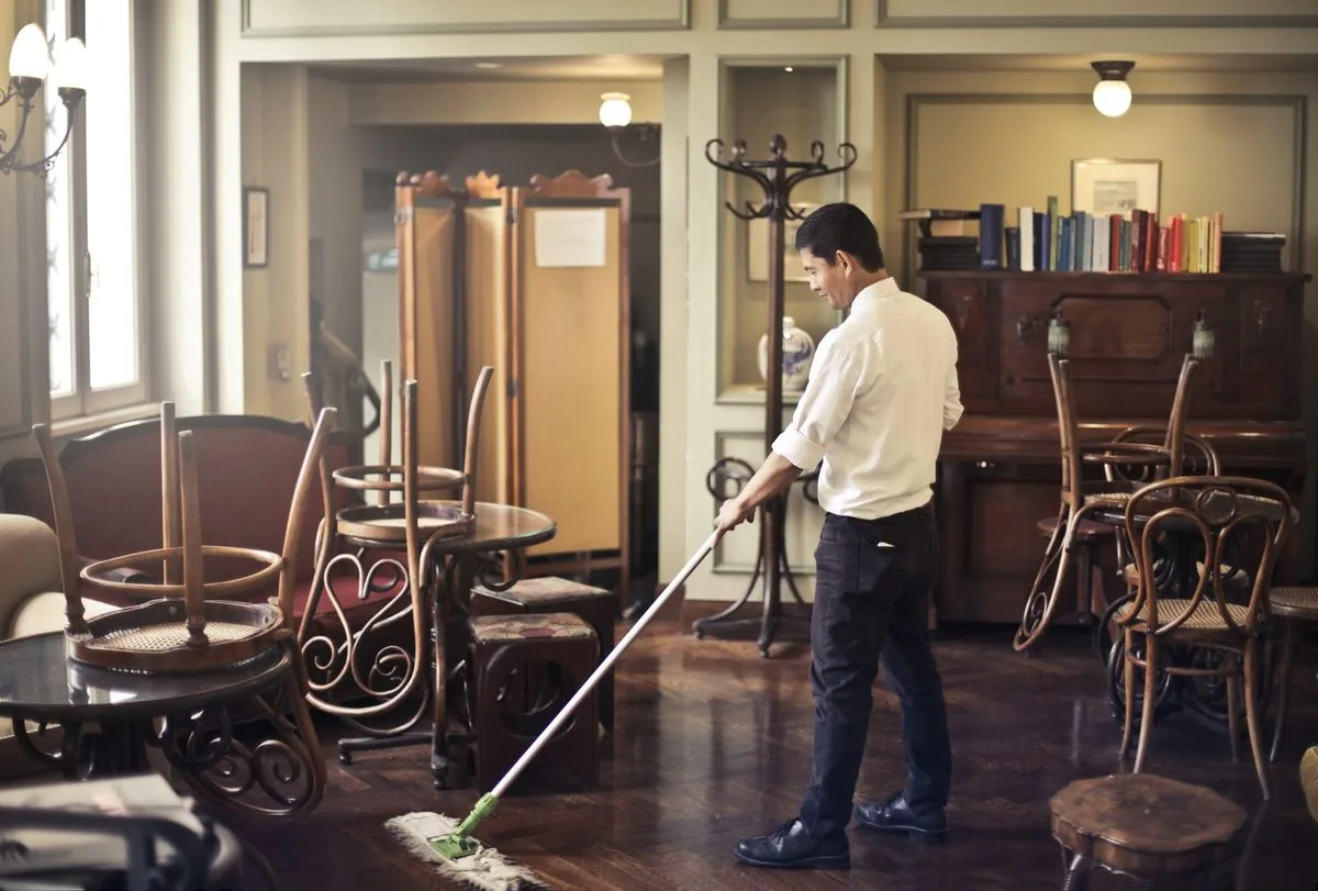 Uniformed cleaner mopping the floor of a large commercial space